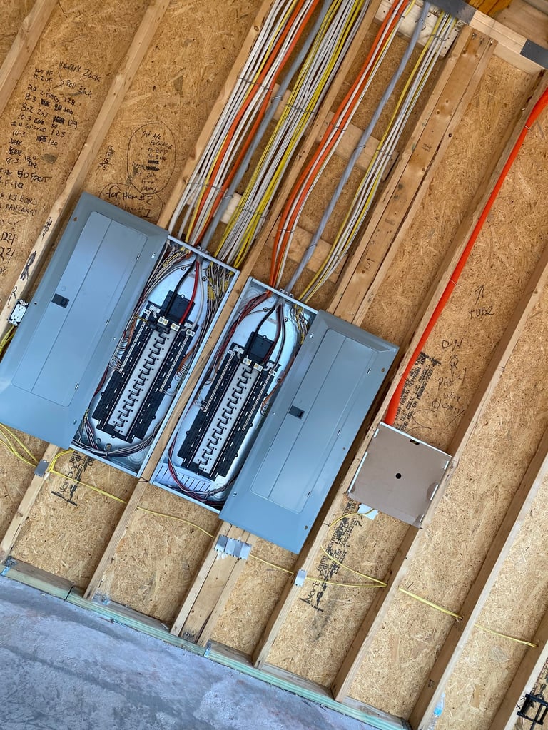 Overhead view of electrical panels and wire conduits mounted on cork wall insulation with organized cable routing