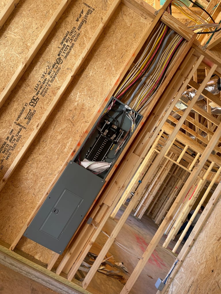 Electrical breaker box with colorful wires installed in a wooden framed ceiling cavity